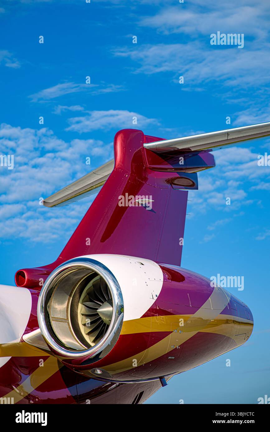 Gros plan vibrant du moteur monté à l'arrière d'un jet privé et du stabilisateur vertical contre un ciel bleu clair. Puissance aéronautique et luxe. Banque D'Images