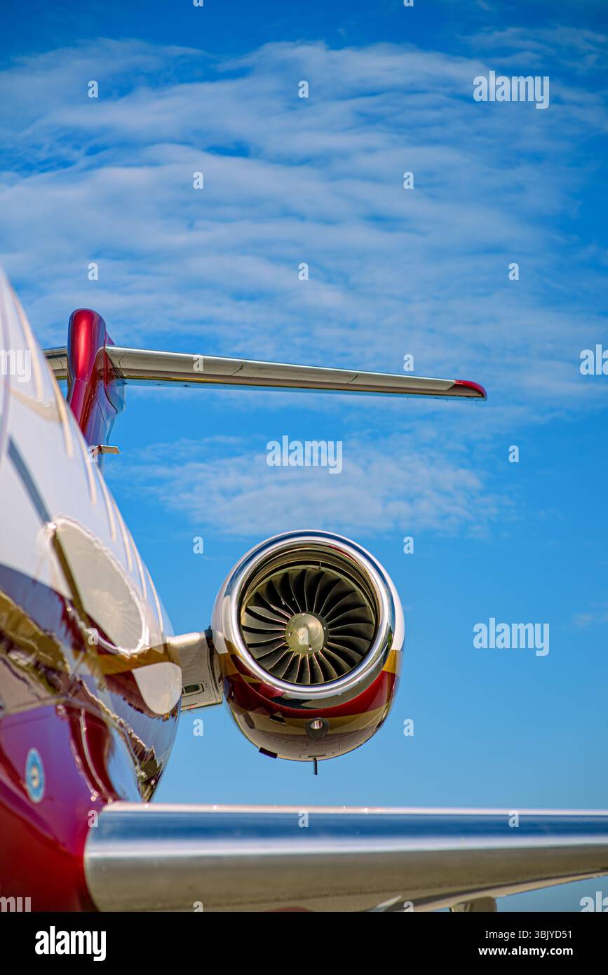 Turboréacteur et section de queue sur un jet d'affaires privé avec livrée rouge et or. Photographié contre un ciel bleu vif avec des nuages dispersés. Banque D'Images