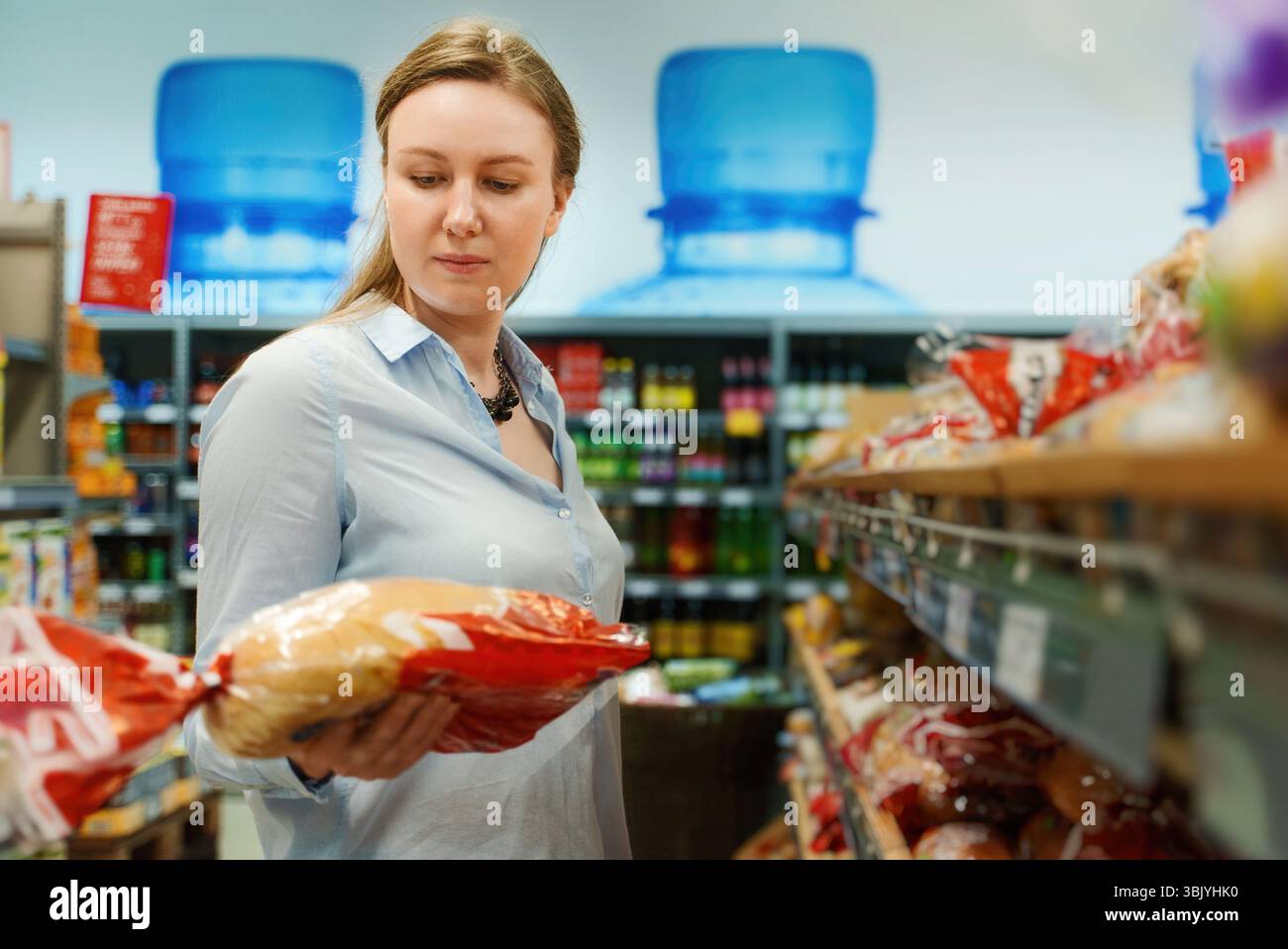Une femme choisit du pain à l'épicerie. Banque D'Images
