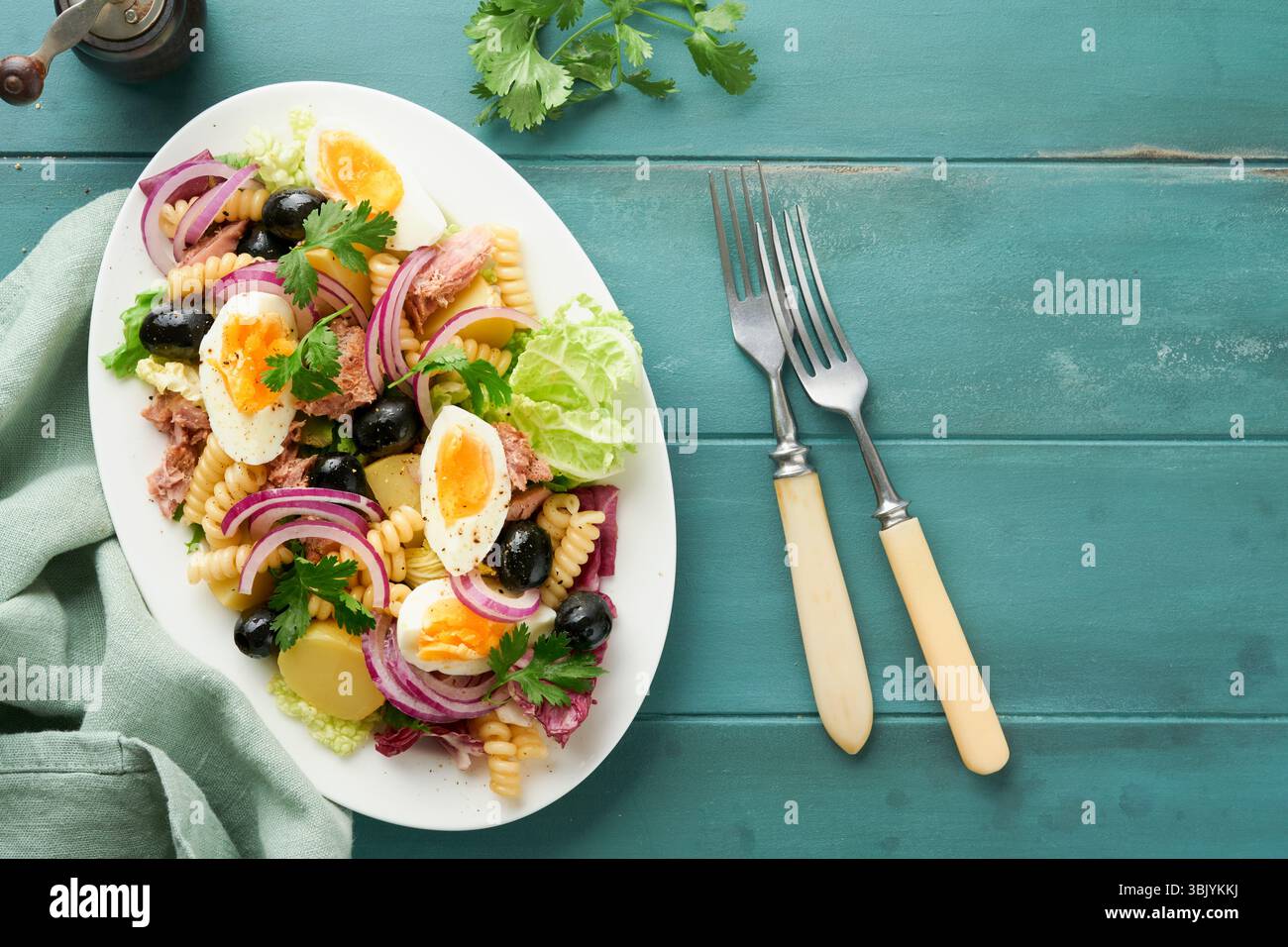 Salade de thon avec pâtes, oeufs, pommes de terre, olives, oignons rouges et sauce dans une assiette blanche sur une vieille backgrou rustique en bois turquoise Banque D'Images Salade de thon avec pâtes, oeufs, pommes de terre, olives, oignons rouges et sauce dans une assiette blanche sur une vieille backgrou rustique en bois turquoise Banque D'Images