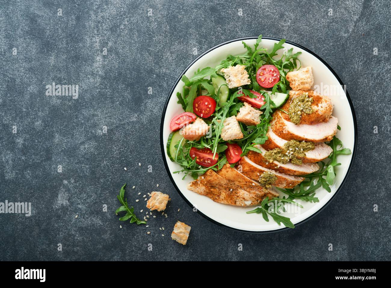Salade fraîche avec filet de poulet grillé, laitue, roquette, épinards, tomates, sauce concombre et pesto, graines de sésame avec olive Banque D'Images Salade fraîche avec filet de poulet grillé, laitue, roquette, épinards, tomates, sauce concombre et pesto, graines de sésame avec olive Banque D'Images