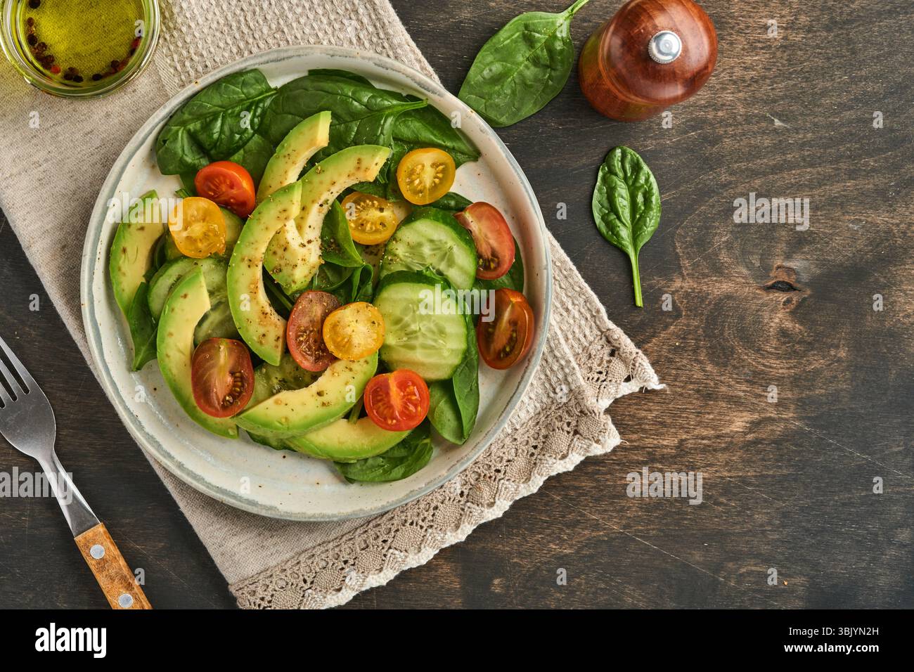 Avocat, rouge, jaune, tomate cerise noire, épinards et concombre salade fraîche avec épices poivre et huile d'olive dans un bol gris vieux WO Banque D'Images Avocat, rouge, jaune, tomate cerise noire, épinards et concombre salade fraîche avec épices poivre et huile d'olive dans un bol gris vieux WO Banque D'Images