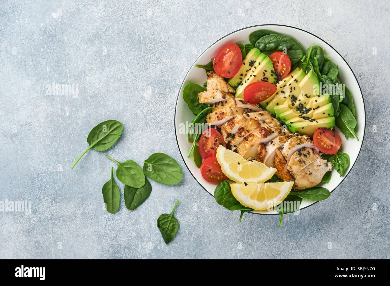 Salade verte fraîche avec filet de poulet grillé, épinards, tomates, avocat, citron et graines de sésame noir avec huile d'olive en blanc Banque D'Images Salade verte fraîche avec filet de poulet grillé, épinards, tomates, avocat, citron et graines de sésame noir avec huile d'olive en blanc Banque D'Images