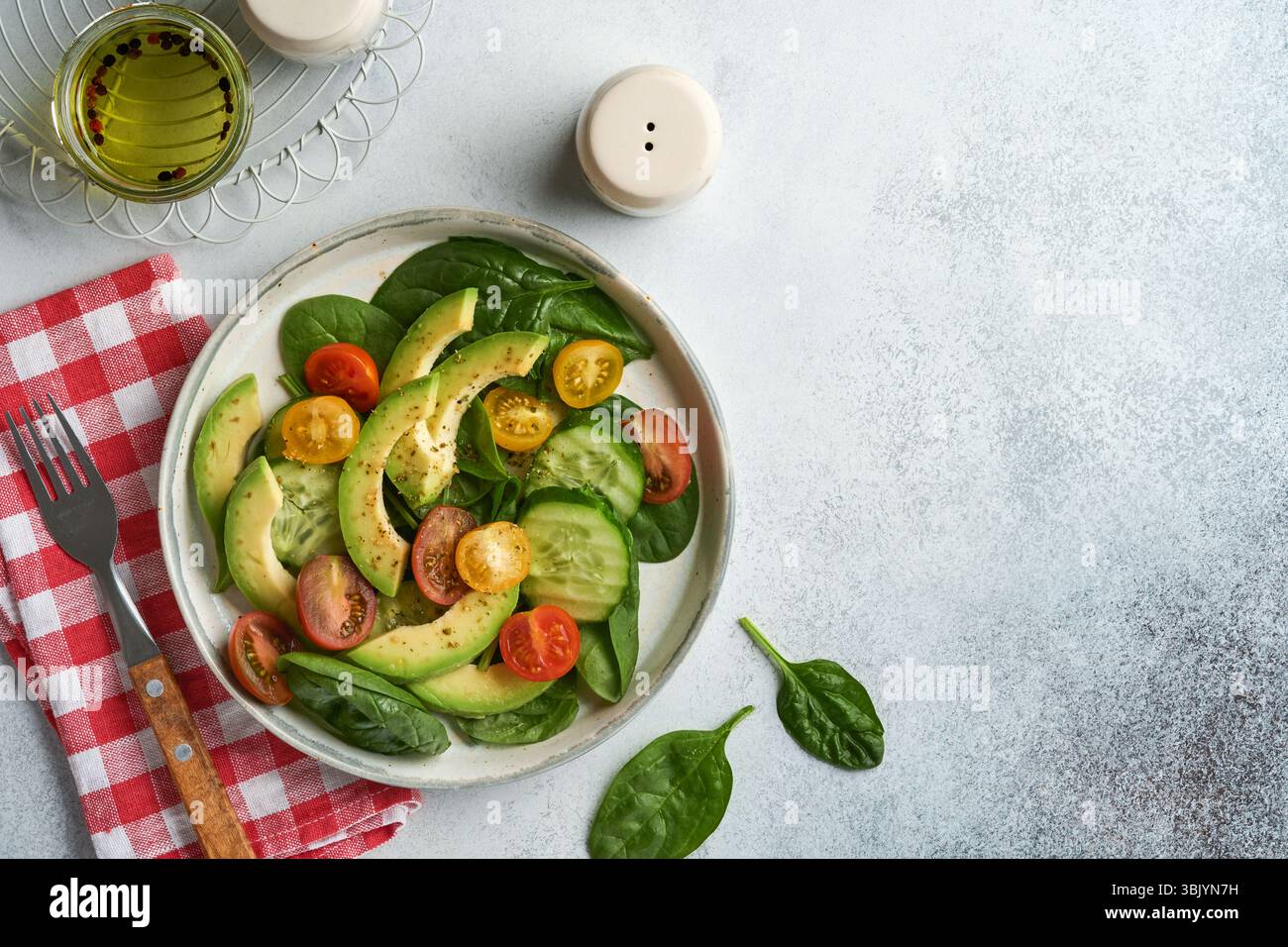 Avocat, rouge, jaune, tomate cerise noire, épinards et concombre salade fraîche avec épices poivre et huile d'olive dans un bol gris sur gre Banque D'Images Avocat, rouge, jaune, tomate cerise noire, épinards et concombre salade fraîche avec épices poivre et huile d'olive dans un bol gris sur gre Banque D'Images