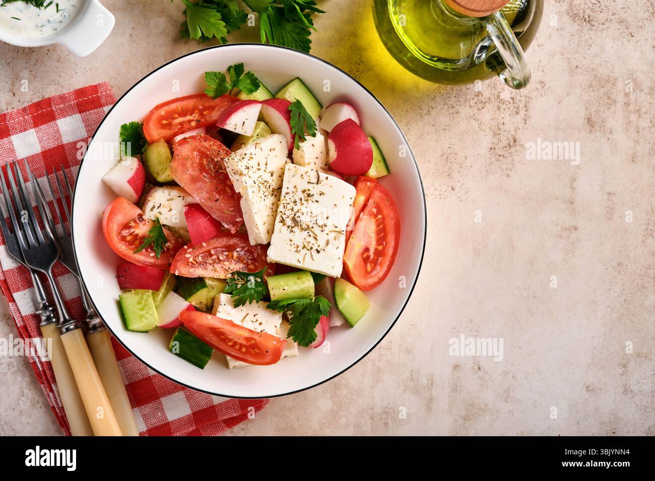 Radis, concombre, tomate, poivre et feta avec épices poivre et huile d'olive dans un bol blanc sur ardoise grise, pierre ou béton Banque D'Images Radis, concombre, tomate, poivre et feta avec épices poivre et huile d'olive dans un bol blanc sur ardoise grise, pierre ou béton Banque D'Images