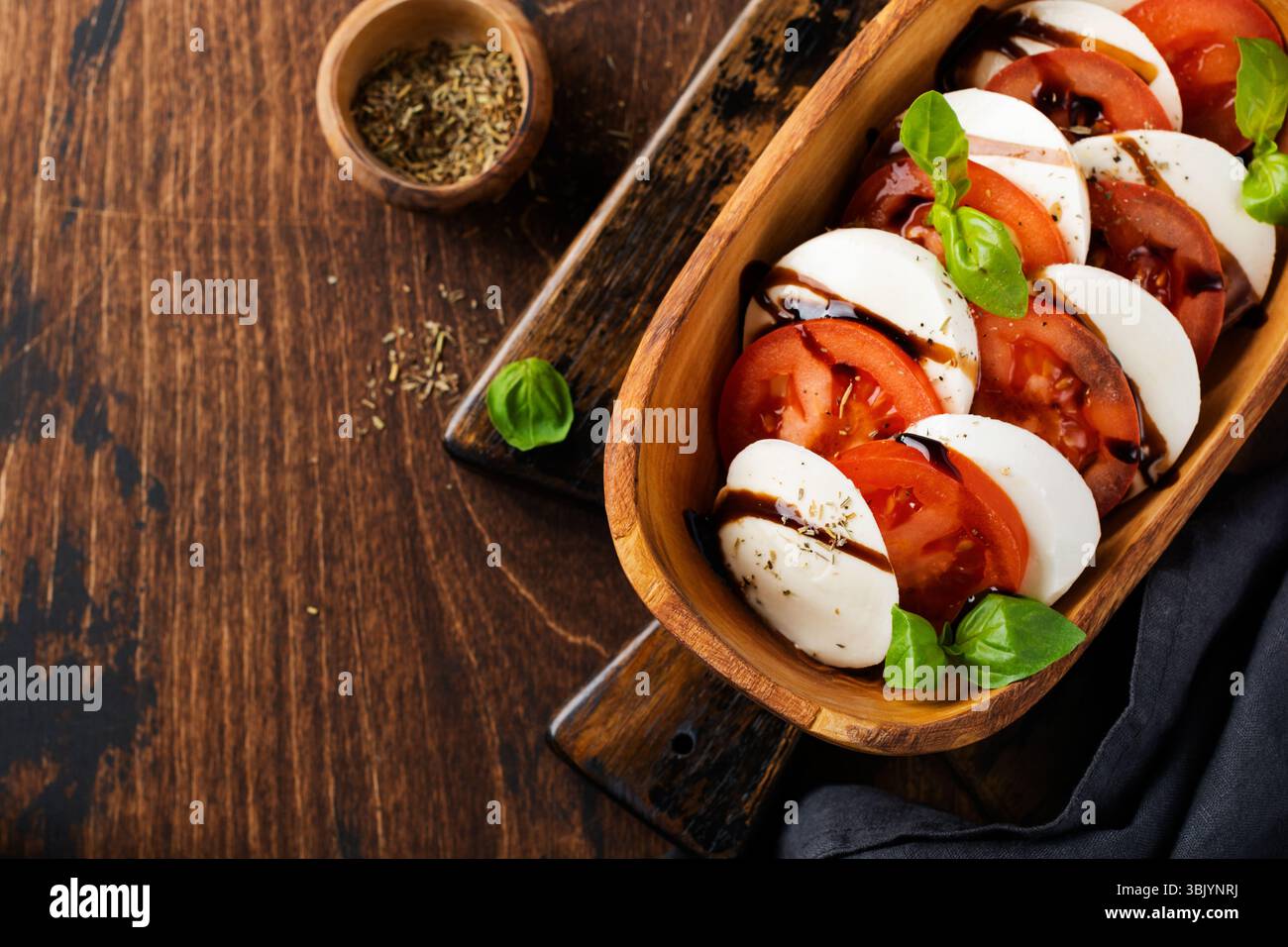 Salade italienne traditionnelle Caprese dans un bol en bois d'olive sur fond rustique ancien. Vue de dessus Banque D'Images Salade italienne traditionnelle Caprese dans un bol en bois d'olive sur fond rustique ancien. Vue de dessus Banque D'Images