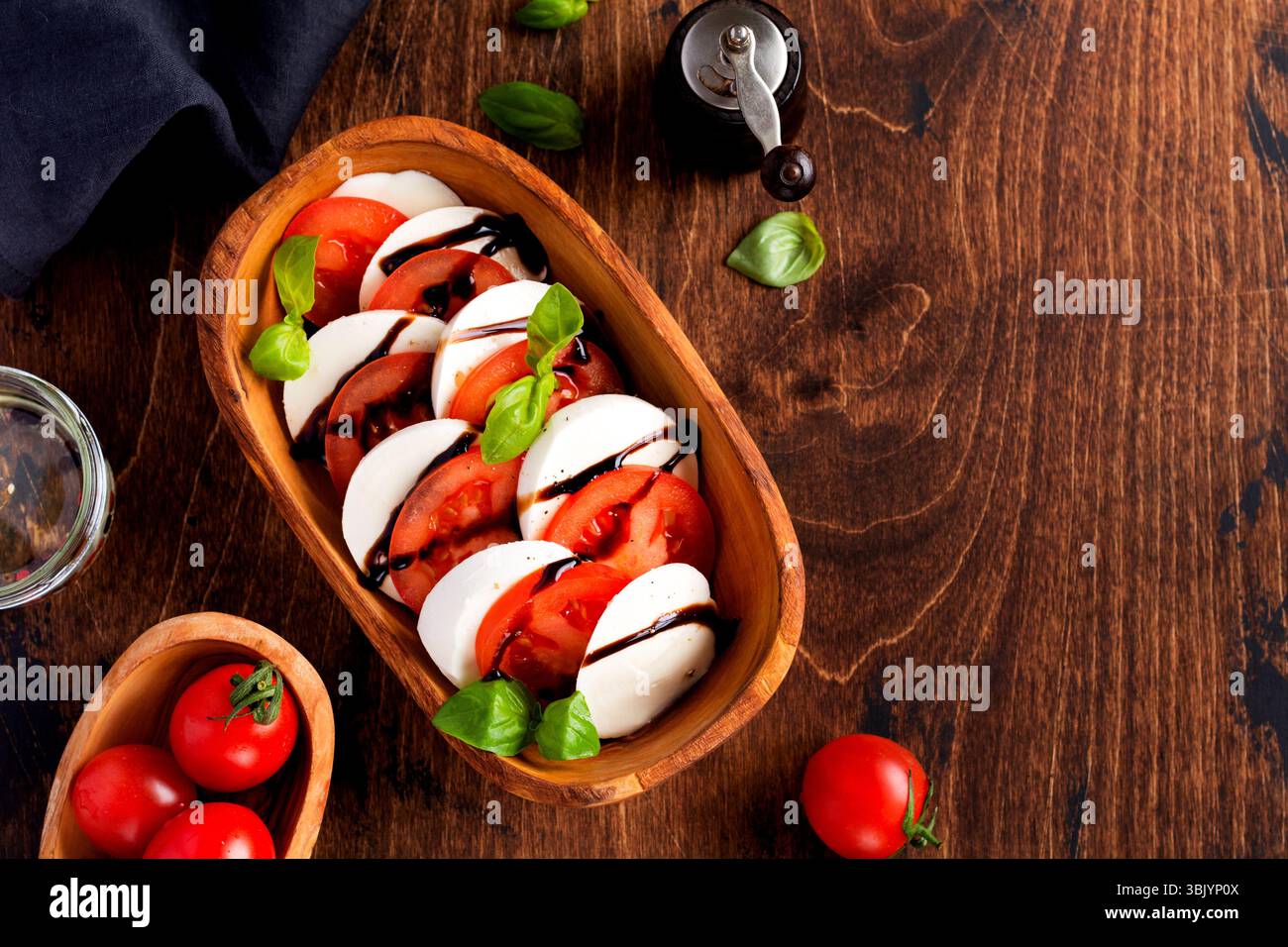 Salade Caprese cuisine italienne avec tomates mûres, basilic frais du jardin et fromage mozzarella dans un bol en bois d'olive sur un vieux dos rustique Banque D'Images Salade Caprese cuisine italienne avec tomates mûres, basilic frais du jardin et fromage mozzarella dans un bol en bois d'olive sur un vieux dos rustique Banque D'Images