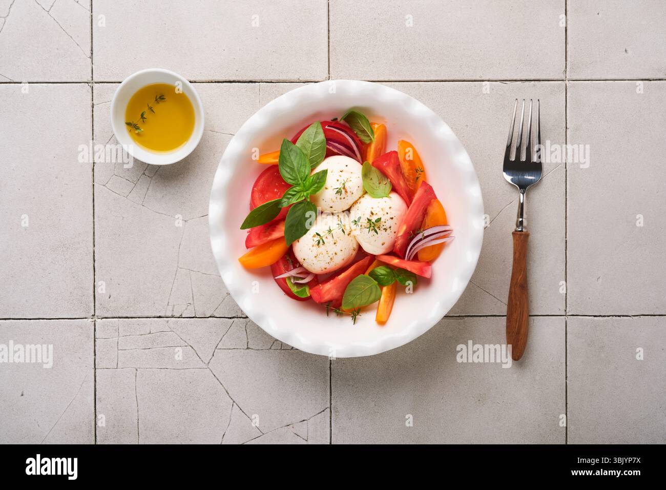 Salade Caprese. Salade italienne caprese avec tomates tranchées, fromage mozzarella, basilic, huile d'olive dans une assiette blanche sur backgro blanc Banque D'Images Salade Caprese. Salade italienne caprese avec tomates tranchées, fromage mozzarella, basilic, huile d'olive dans une assiette blanche sur backgro blanc Banque D'Images