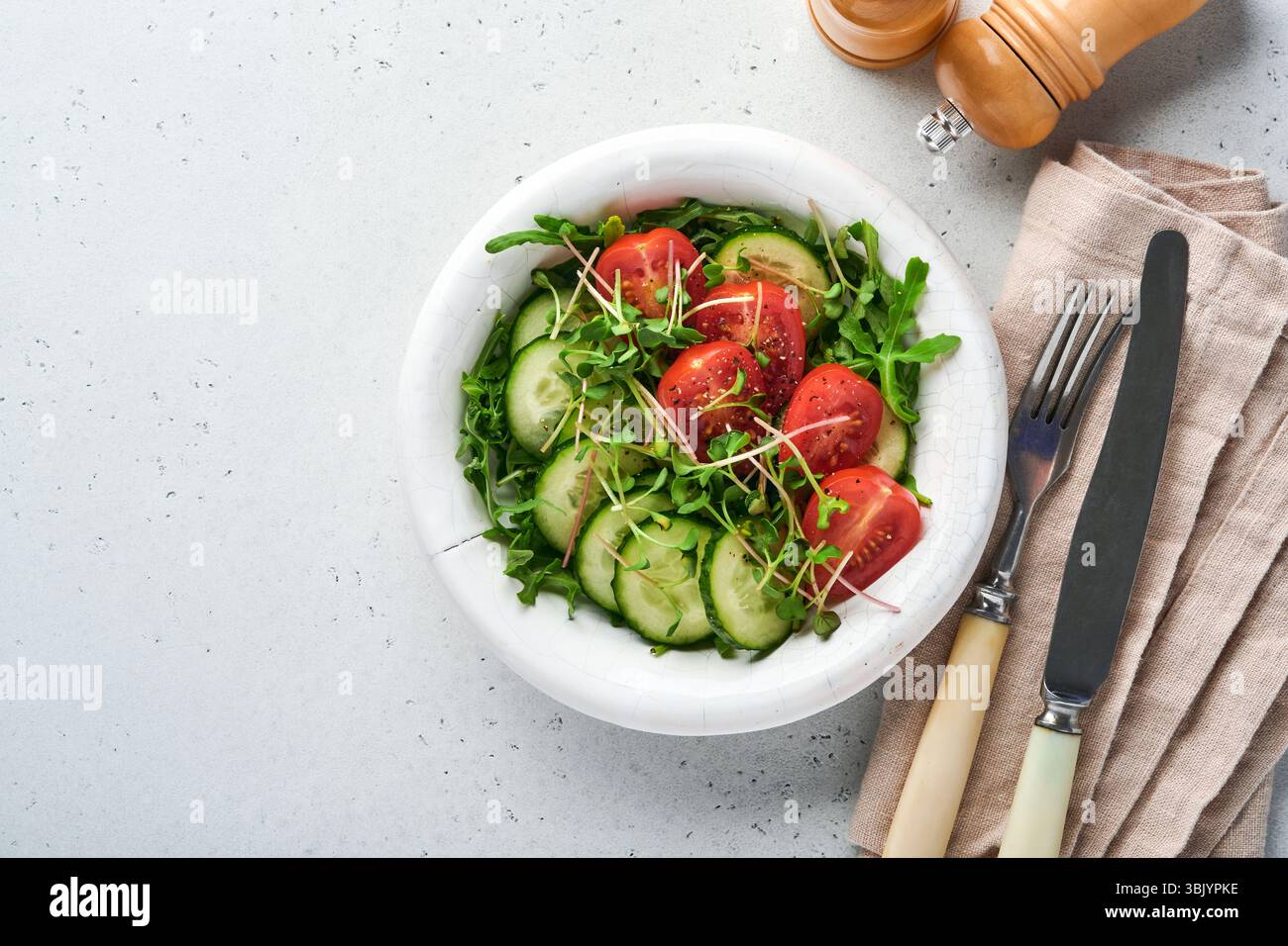 Salade fraîche avec tomate, concombre, légumes, radis microverts dans une assiette blanche sur fond de pierre grise. Vue de dessus. CON Banque D'Images Salade fraîche avec tomate, concombre, légumes, radis microverts dans une assiette blanche sur fond de pierre grise. Vue de dessus. CON Banque D'Images
