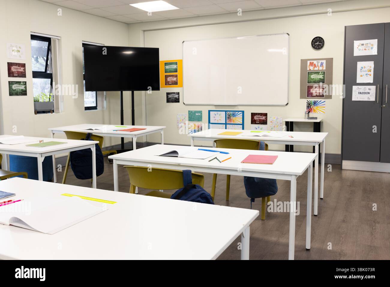 Salle de classe vide avec des bureaux bien agencés, des cahiers colorés et un tableau blanc, à l'école Banque D'Images