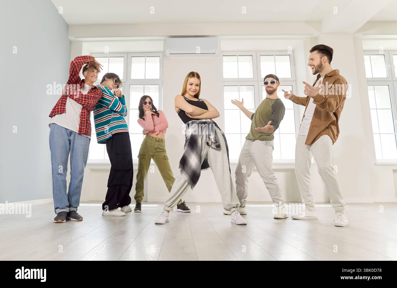Groupe de danse de jeunes gens sympas dansant activement à l'intérieur, se déplaçant posant dans un studio moderne lumineux Banque D'Images