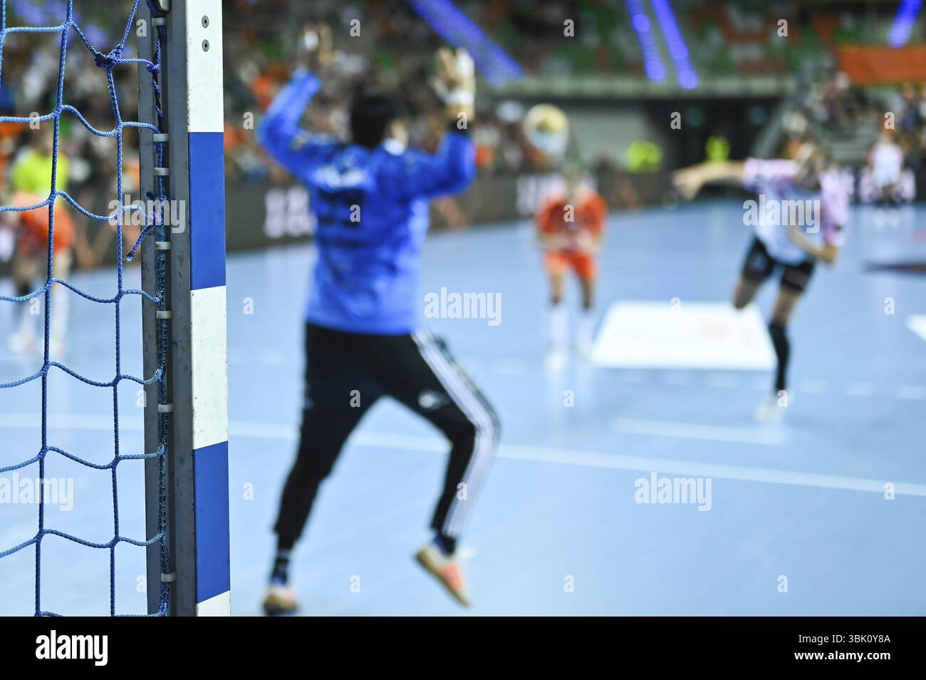 Détail du poteau de but de handball avec filet et joueurs en arrière-plan Banque D'Images