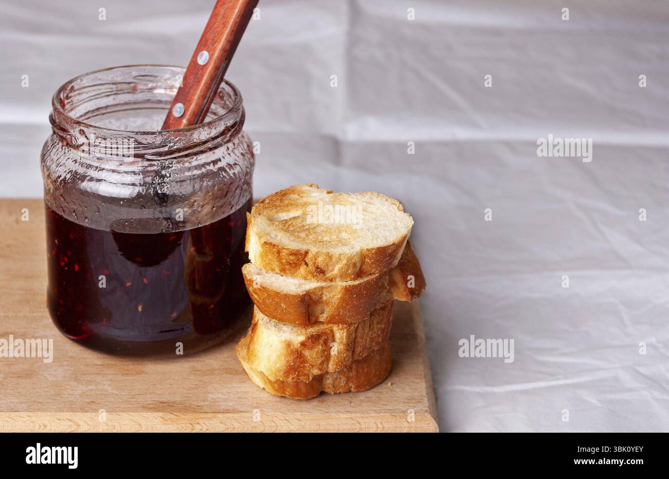 Il y a un pot de confiture de framboises et des tranches de pain séché sur la table, copiez l'endroit Banque D'Images