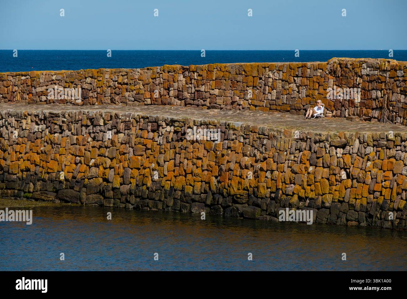 Senior profitant d'un peu de temps sur le quai de Cellardyke Harbour, Fife, Écosse. Banque D'Images