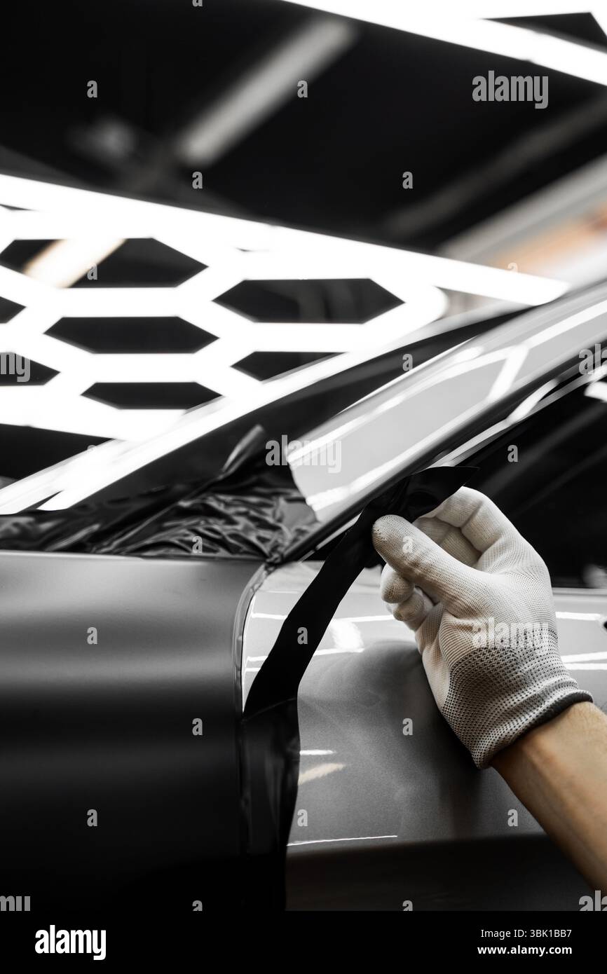 L'application d'habillage modifie l'apparence du véhicule. Emballage en vinyle pour voiture à panneau complet. L'installation à grande échelle de film vinyle transforme l'extérieur du véhicule Banque D'Images