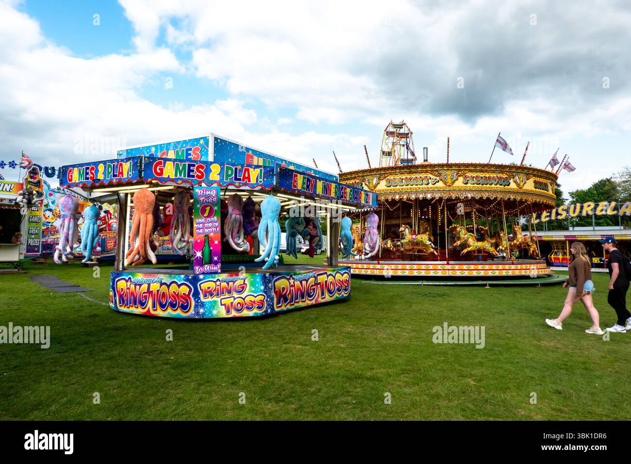 Une scène de foire animée à Saffron Walden, en Angleterre, avec un carrousel et des parties de lancer d'anneau sous un ciel nuageux. Banque D'Images