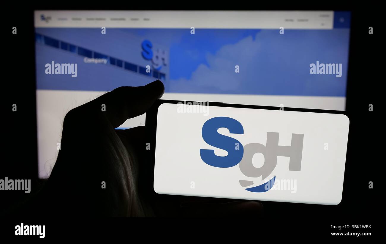 Stuttgart, Allemagne - 04-26-2025, personne tenant le téléphone portable avec le logo de la société de logistique SG Holdings Co. Ltd sur l'écran devant la page web. Banque D'Images