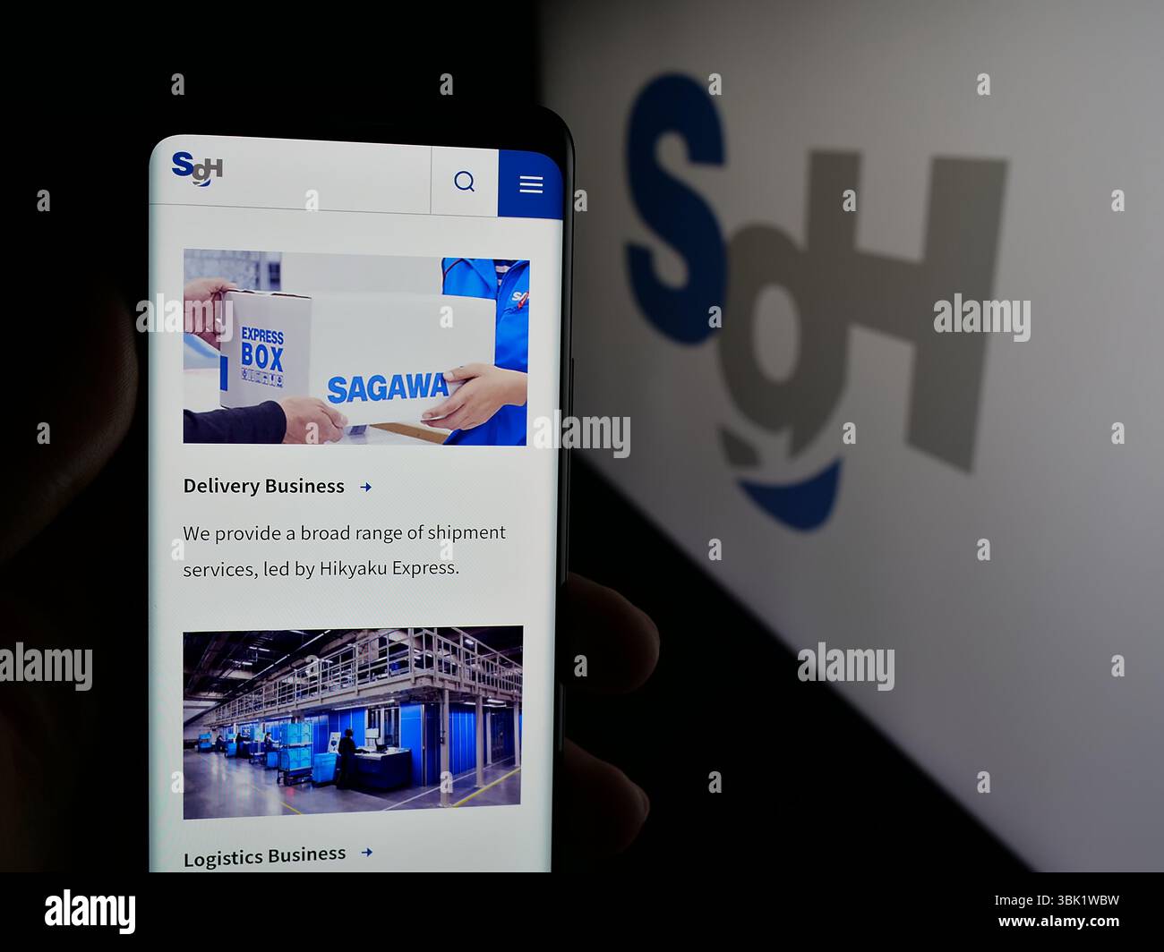 Stuttgart, Allemagne - 04 26 2025 : personne tenant un téléphone portable avec la page web de la société de logistique SG Holdings Co. Ltd sur l'écran devant le logo. Banque D'Images