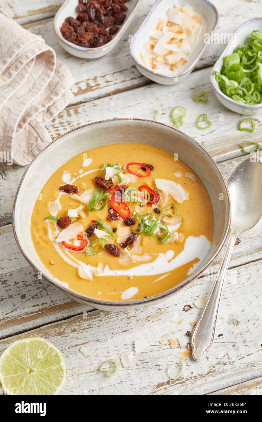 Soupe crémeuse de lentilles à la citronnelle, au lait de coco et au piment rouge, servie dans un bol – chaude, épicée et à base de plantes, parfaite pour le déjeuner ou un dîner léger. Banque D'Images