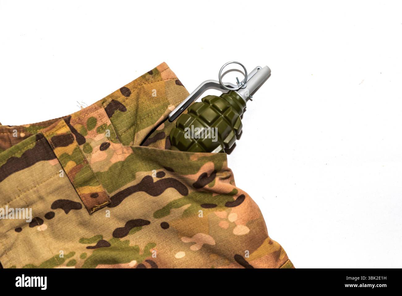 Grenade à main factice en plastique placée dans la poche du pantalon camouflage de style militaire. Image symbolique de la guerre, du danger ou de l'entraînement militaire. Utilisation éditoriale Banque D'Images