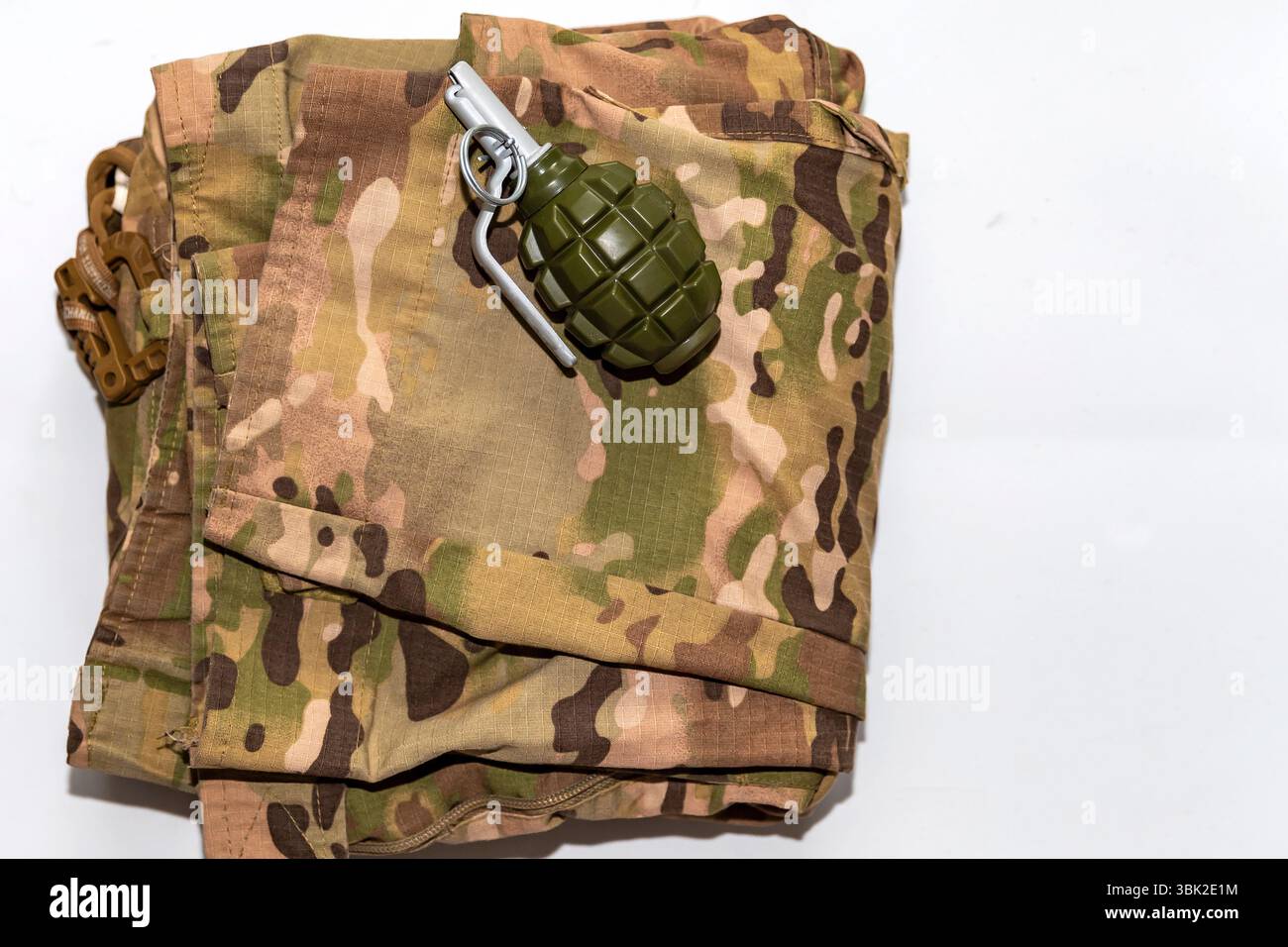 Grenade à main factice en plastique placée dans la poche du pantalon camouflage de style militaire. Image symbolique de la guerre, du danger ou de l'entraînement militaire. Utilisation éditoriale Banque D'Images