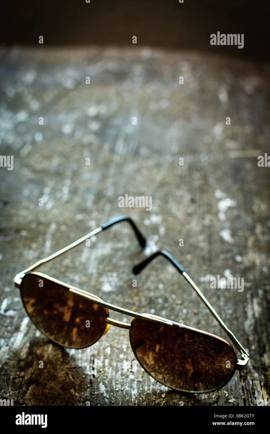 Les lunettes de soleil vintage élégantes reposent sur une surface en bois altérée, reflétant la lumière douce diffusée. Banque D'Images