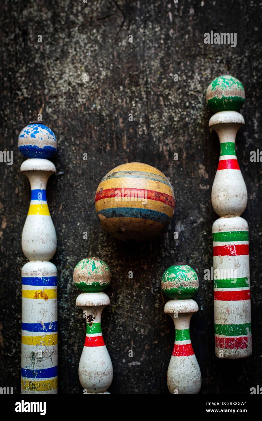Un jeu de bowling classique présente des épingles en bois portées dans des couleurs vives et une balle rayée, affichée sur une surface rustique qui améliore le nostalgique Banque D'Images