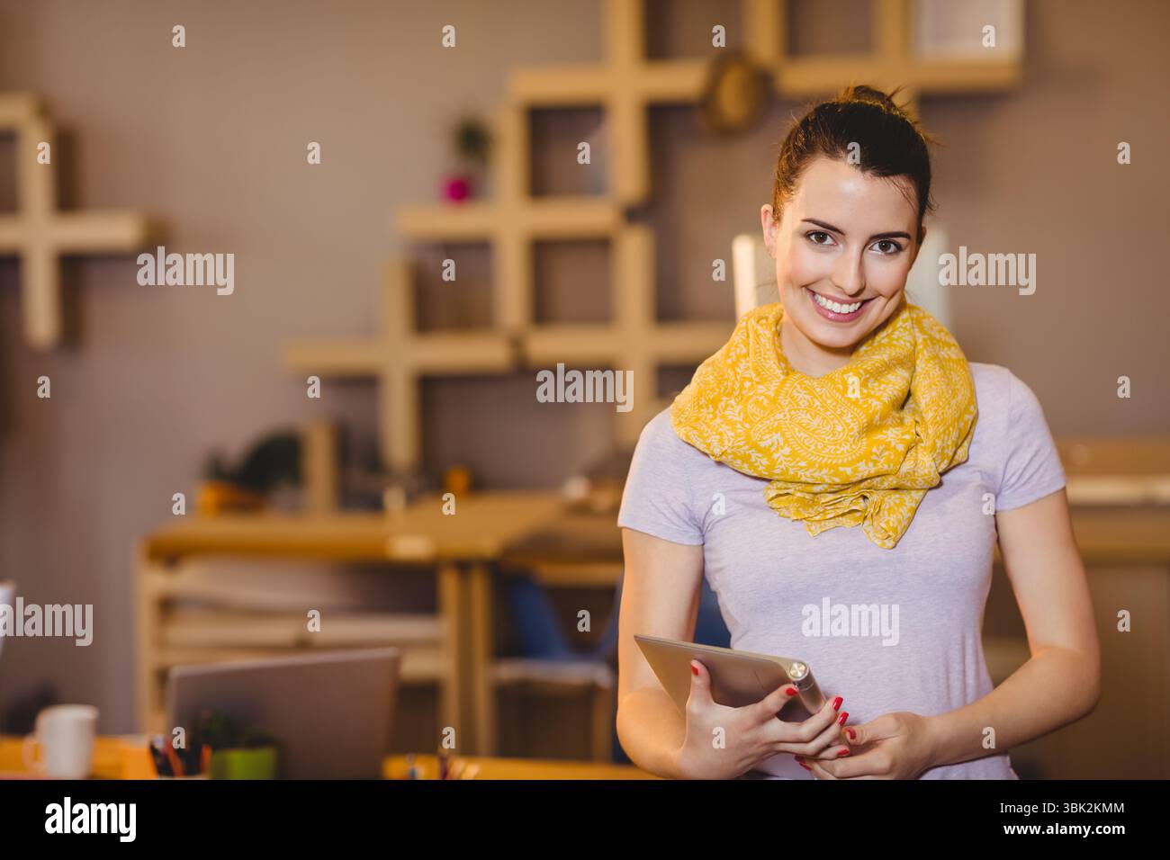 Ordinateur tablette reposant sur le bureau à côté de tasse à café et ordinateur portable avec étagères modulaires en bois dans le bureau Banque D'Images
