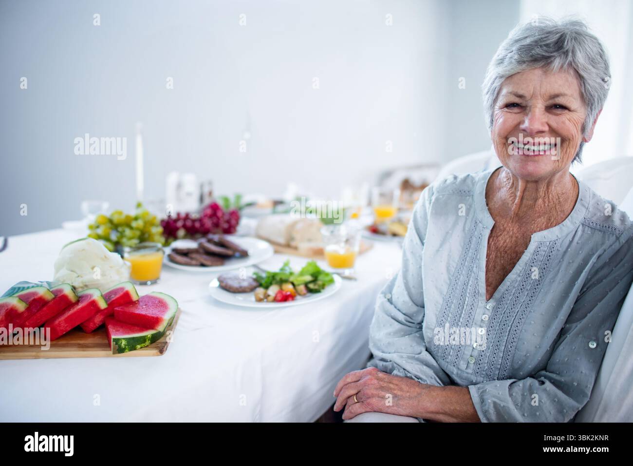 Le petit déjeuner est composé de pastèque, raisins, pain et jus de fruits sur la table à manger de la maison Banque D'Images