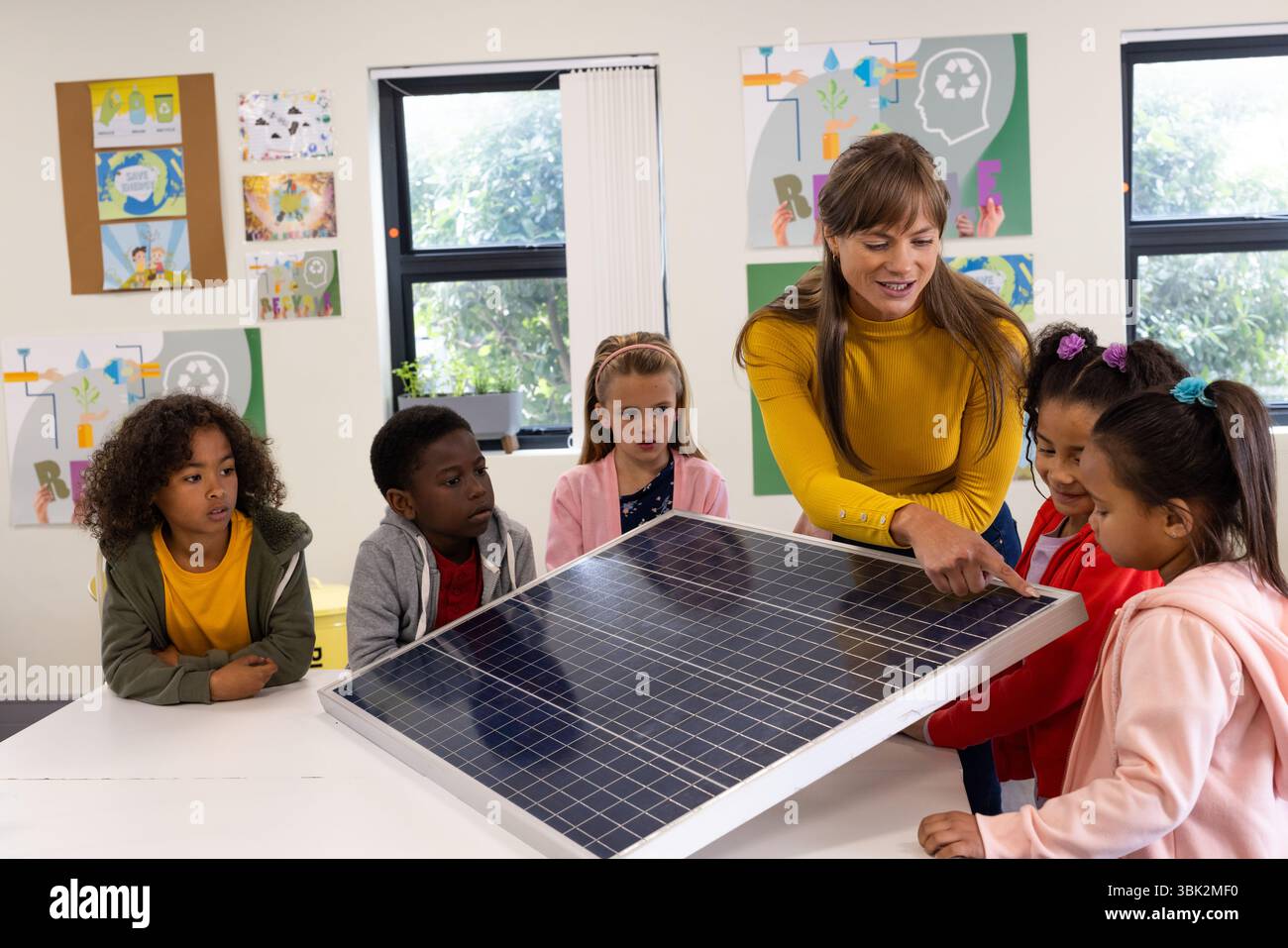 Expliquer le panneau solaire, enseignante engageant divers enfants en classe, à l'école Banque D'Images