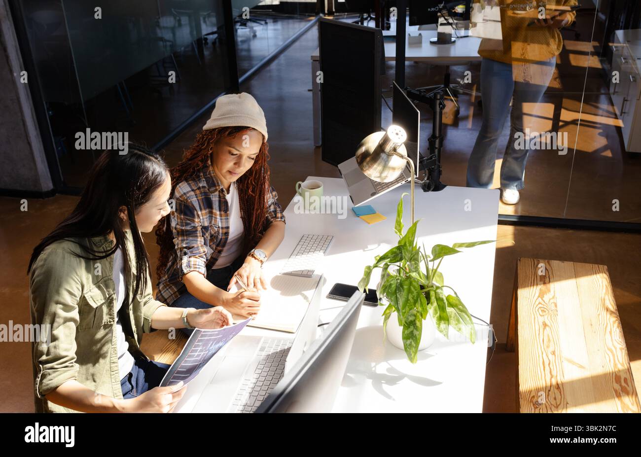Diverses femmes collaborant sur le projet de codage au bureau moderne avec des ordinateurs portables Banque D'Images
