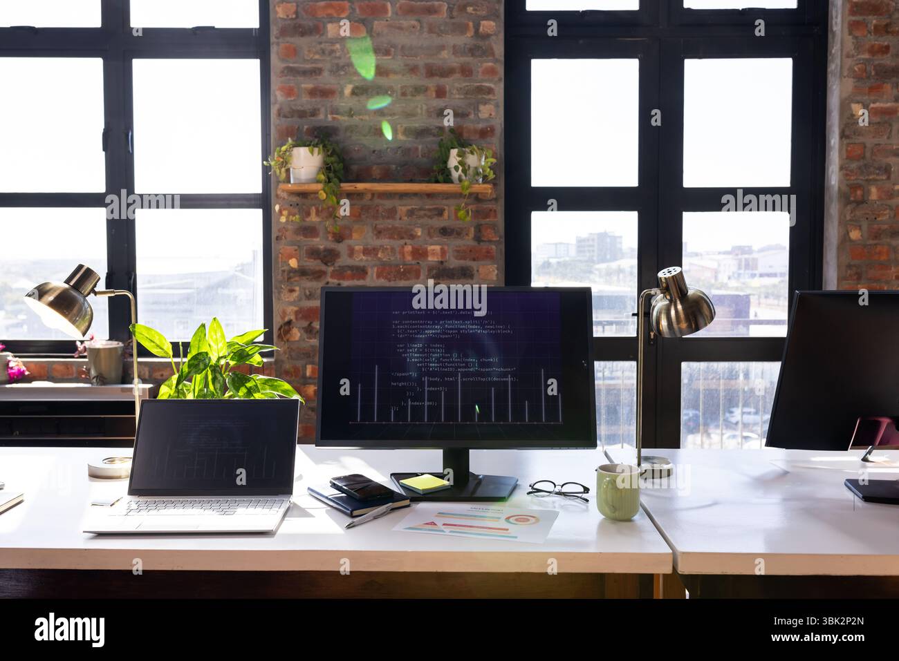 Bureau moderne avec écran d'ordinateur affichant le code et les diagrammes commerciaux Banque D'Images