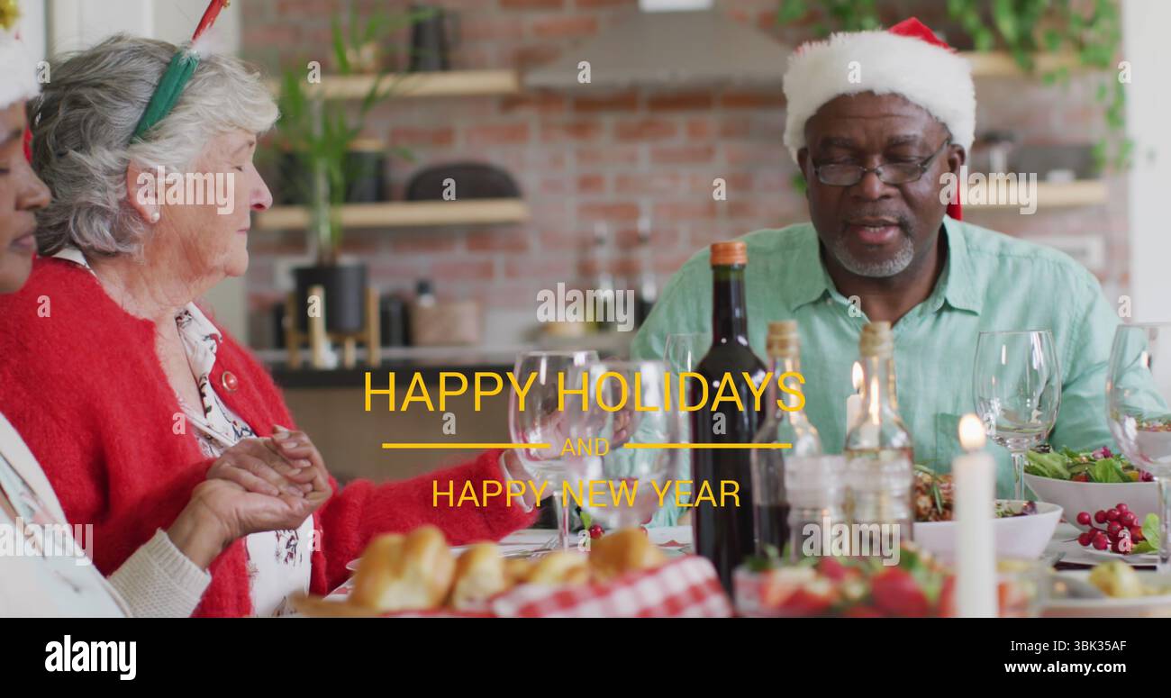 Rassemblement senior partageant le repas de vacances dans la cuisine portant des chapeaux de Père Noël, avec nappe, espace de copie Banque D'Images