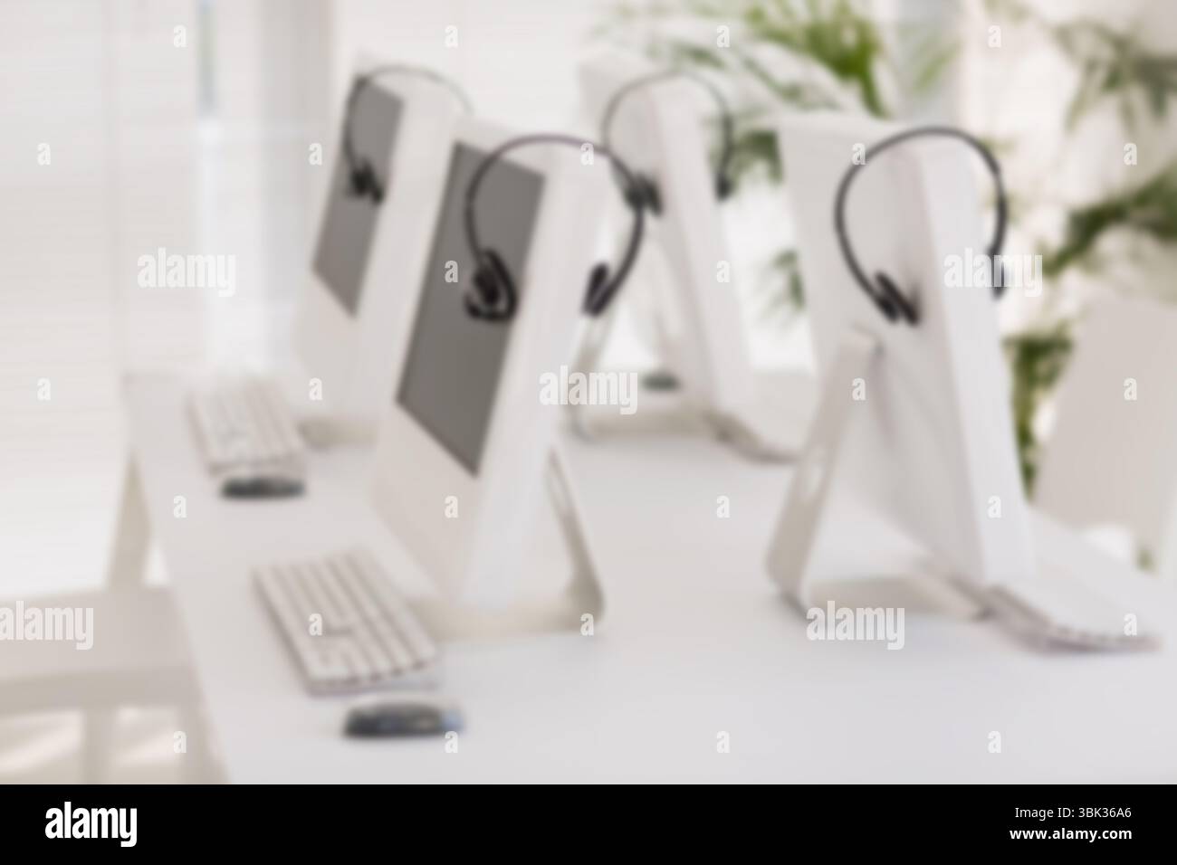 Quatre ordinateurs sont assis sur le bureau dans un design plat avec casques, claviers, souris, stores et plantes Banque D'Images