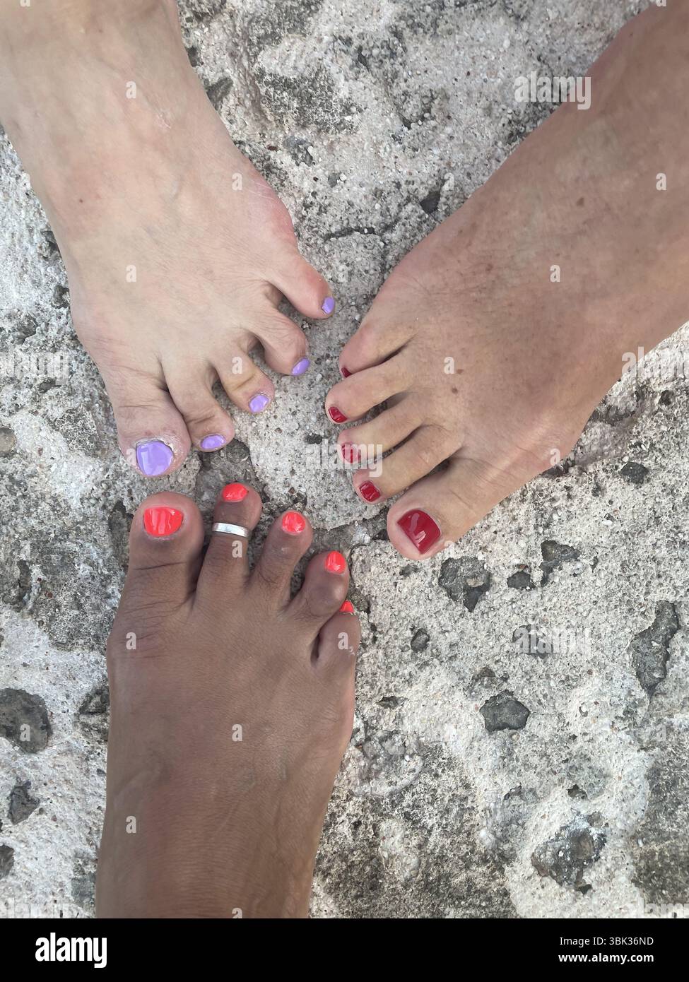 Les pieds des femmes avec des clous d'orteils peints de différentes couleurs. Andrano, Italie Banque D'Images