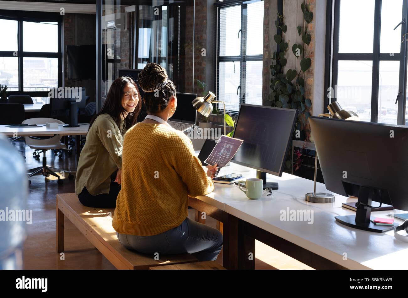 Diverses femmes collaborant sur le projet de codage dans le bureau moderne, partageant des idées et souriant, à la maison Banque D'Images
