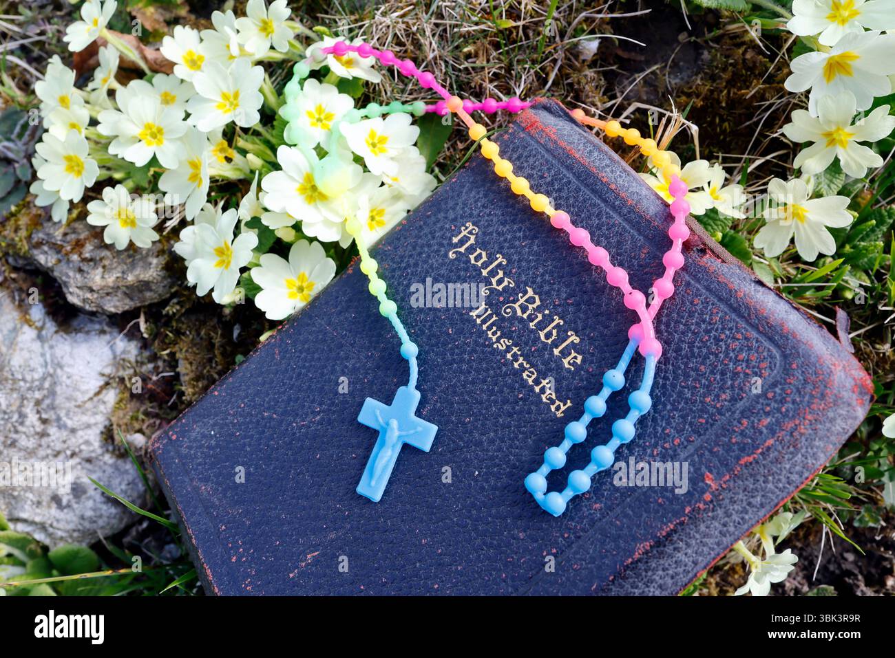 Chapelet en plastique avec des couleurs vives sur une Bible. Banque D'Images
