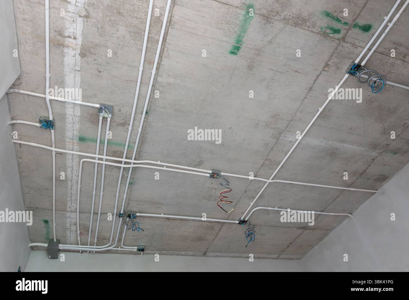 Installation d'un système de conduits électriques sur le plafond en béton exposé d'un bâtiment résidentiel Banque D'Images