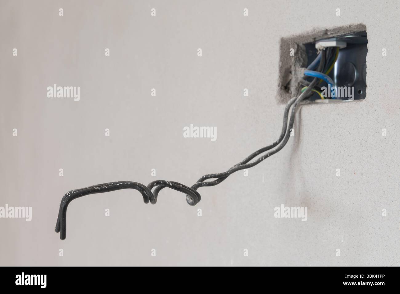 Gros plan des fils électriques exposés dans le mur avec le boîtier électrique partiellement installé Banque D'Images