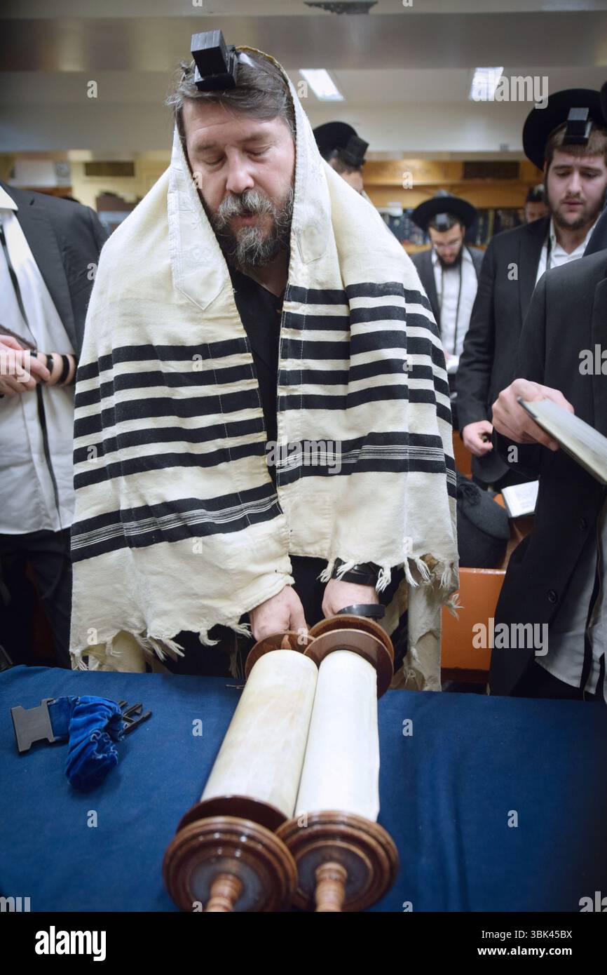 Juif orthodoxe au matin, un homme appelé à la Torah fait une bénédiction avant d'entendre une lecture. À Brooklyn, New York. Banque D'Images