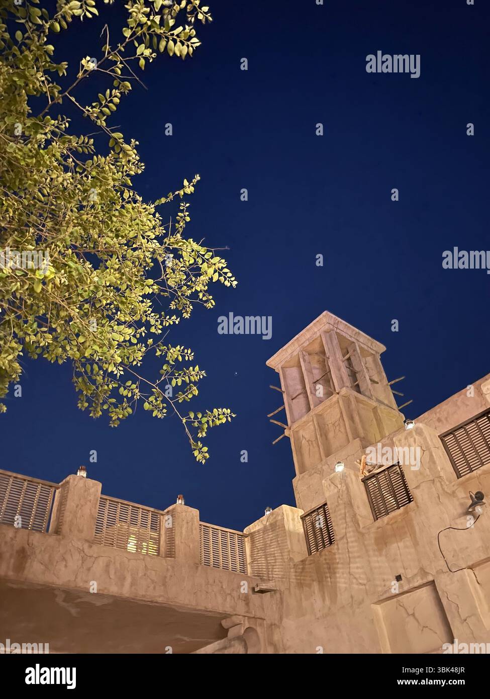 Vue nocturne d'un toit de style arabe traditionnel à Al Seef, Dubaï, avec des arbres silhouettes au premier plan et un éclairage ambiant doux. - Image de stock capturée avec un smartphone