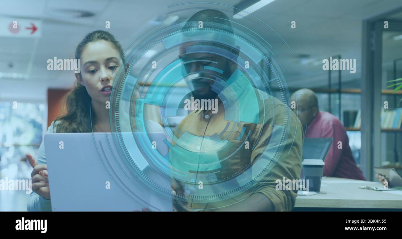 Examinant les collègues regardant l'affichage d'ordinateur portable dans le bureau avec la superposition holographique, cloisons en verre Banque D'Images