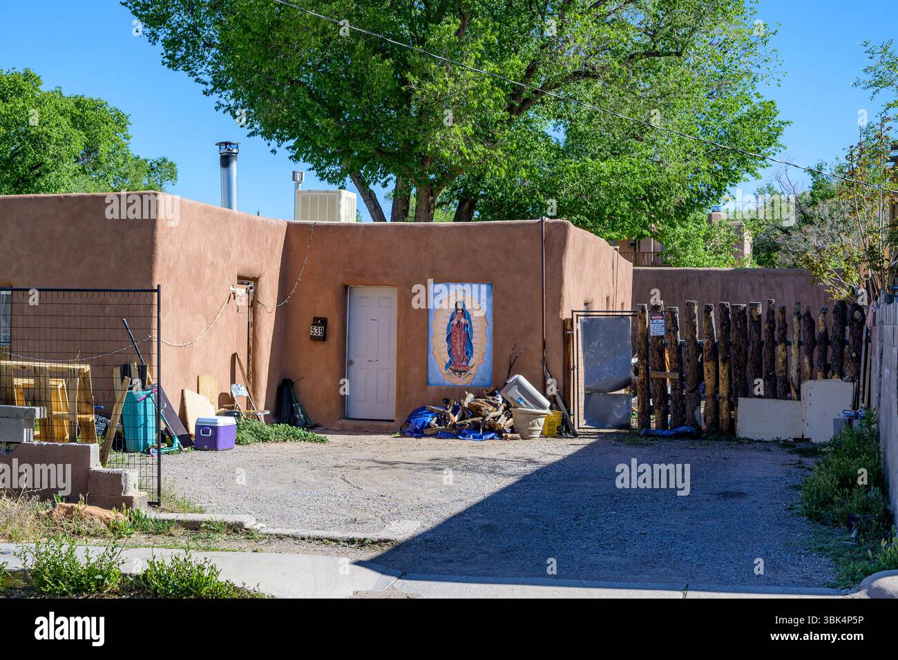 Santa Fe, NM, États-Unis - 15 mai 2025 : maison traditionnelle de style adobe avec peinture commémorative de notre-Dame de Guadalupe près de l'entrée dans un quartier résidentiel Banque D'Images