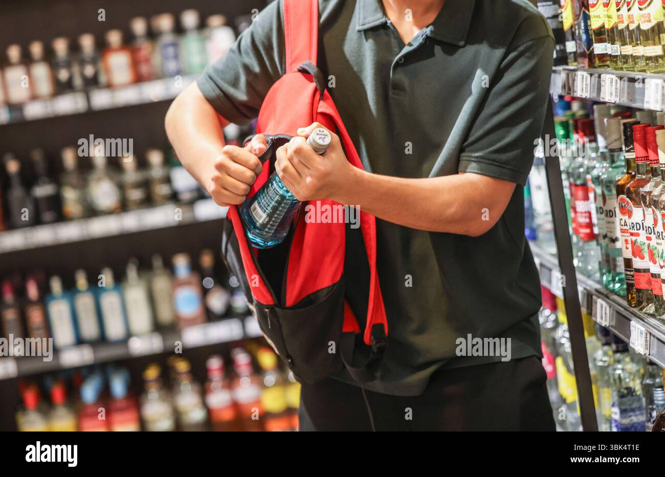Cologne, Allemagne. 18 juin 2025. ILLUSTRATION - Un homme met une bouteille de boisson alcoolisée dans son sac à dos dans un supermarché. Une étude EHI sur le vol à l'étalage et les écarts d'inventaire est publiée. Crédit : Oliver Berg/dpa/Alamy Live News Banque D'Images