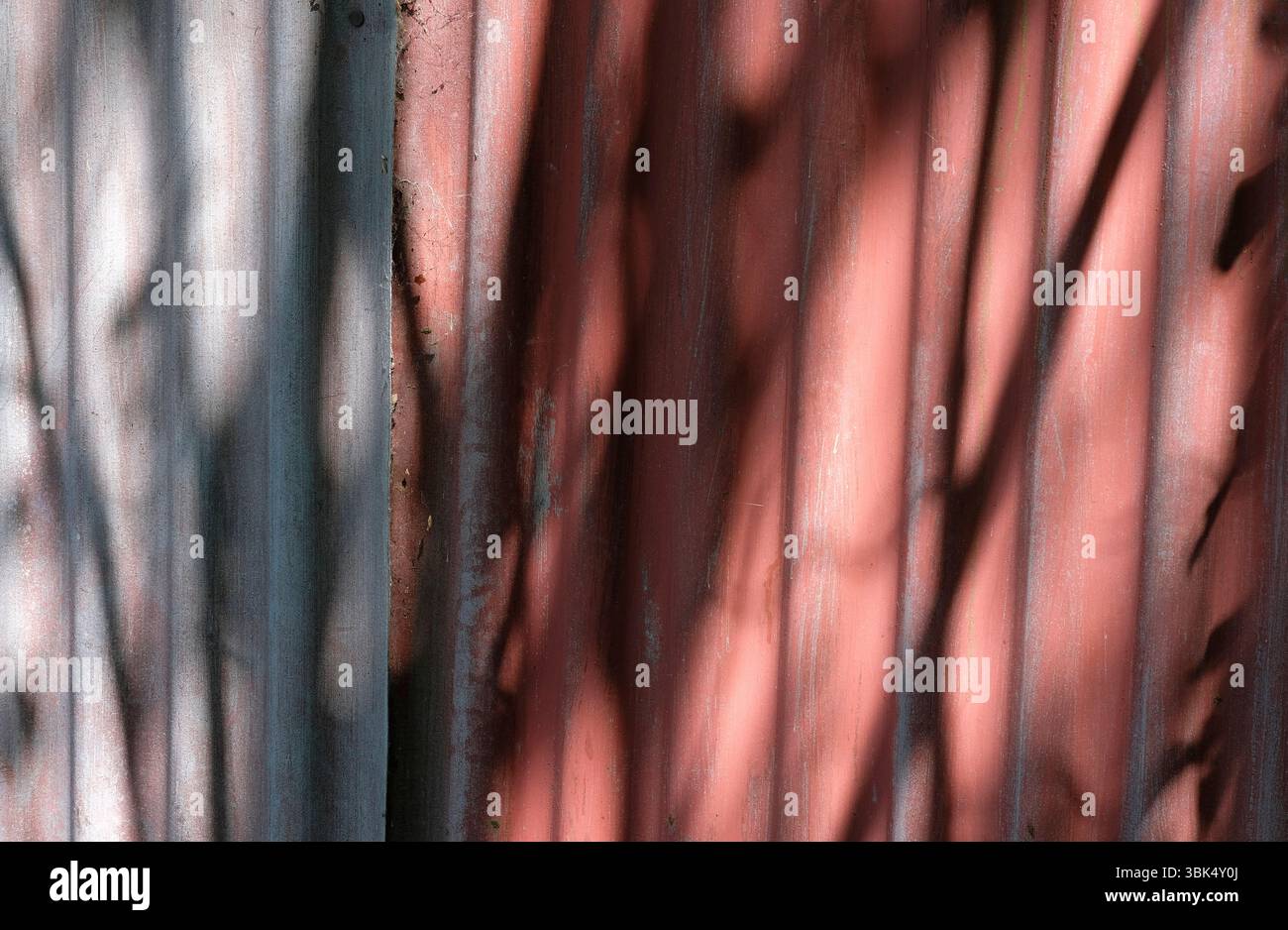 ombres sombres sur le mur en métal ondulé peint en rouge Banque D'Images