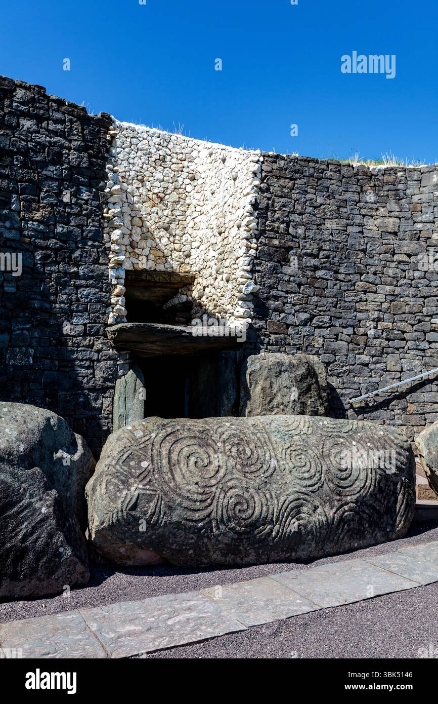 Newgrange, une tombe du passage néolithique, bordée de quartz blanc et de pierres de trottoir très décorées : la principale bordure avec triskelion sur la gauche Banque D'Images