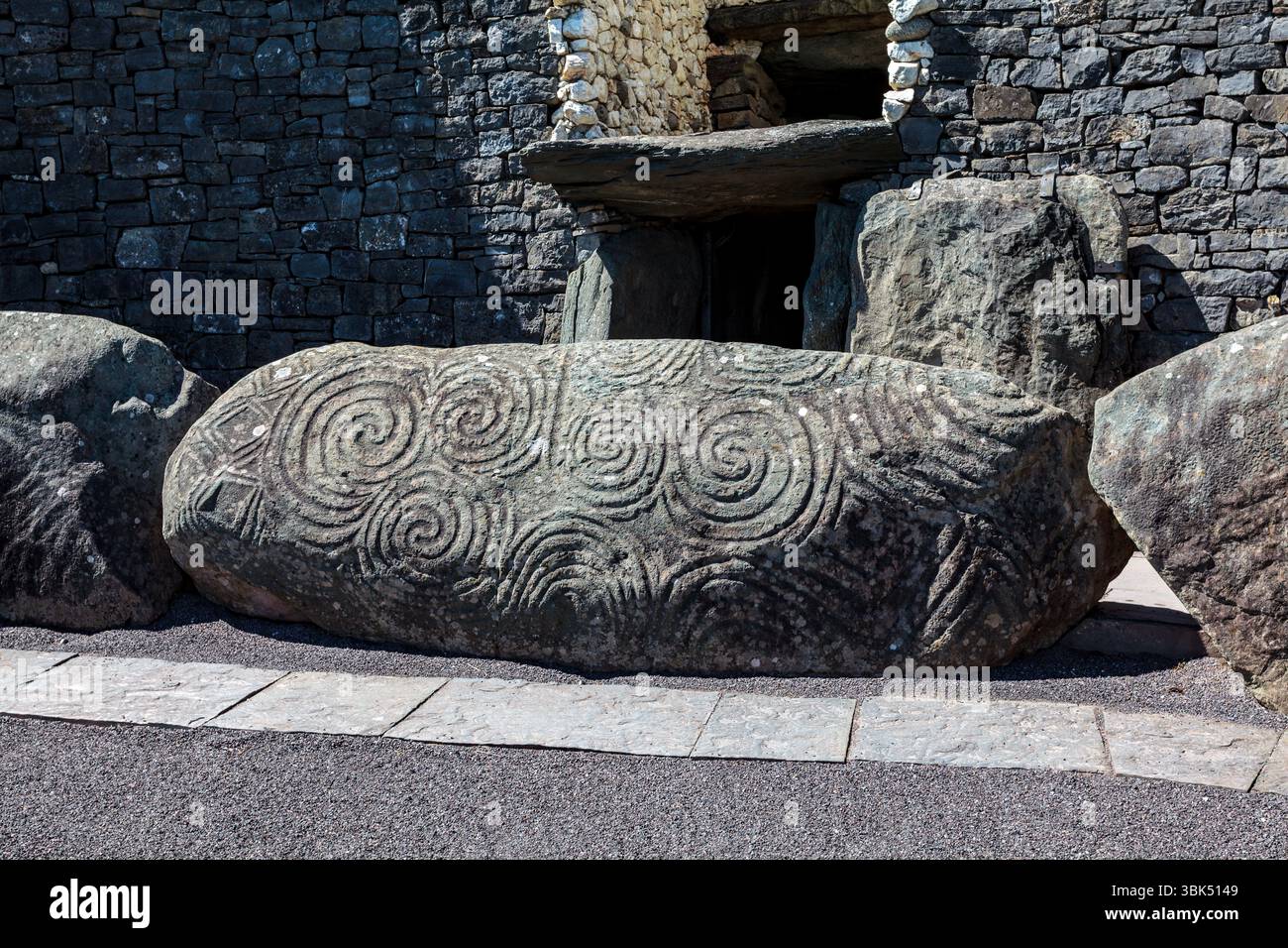 Newgrange, une tombe du passage néolithique, bordée de quartz blanc et de pierres de trottoir très décorées : la principale bordure avec triskelion sur la gauche Banque D'Images