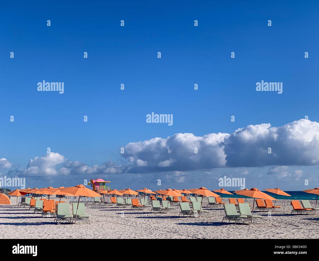 Parapluies orange sur Miami Beach, paysage côtier vibrant avec ciel bleu et nuages Banque D'Images