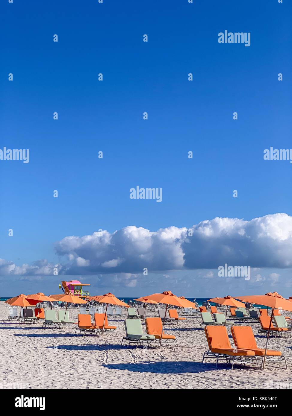 Parapluies orange sur Miami Beach, paysage côtier vibrant avec ciel bleu et nuages Banque D'Images