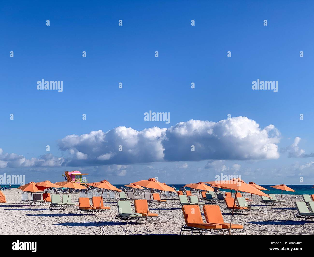 Parapluies orange sur Miami Beach, paysage côtier vibrant avec ciel bleu et nuages Banque D'Images